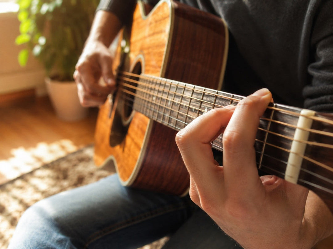Beginner learning guitar fingerpicking with thumb and fingers on an acoustic